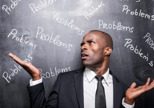 problems-all-around-me-depressed-african-man-formalwear-standing-against-blackboard-with-inscription-problems-gesturing_425904-32552